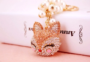 Detail of fox head keychain with rhinestones, faux pearls and gold hardware