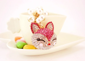 Detail of fox charm keychain with pink crystals and pearls on a white heart cup