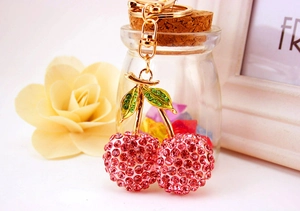 Detail of pink crystal cherry keychain with gold base and green enamel leaves