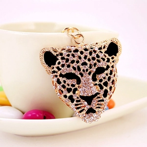 Luxury leopard head keychain with sparkling rhinestones on a white coffee cup background