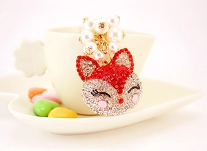 Sparkling fox keychain with red rhinestones and faux pearls on a white petal cup edge