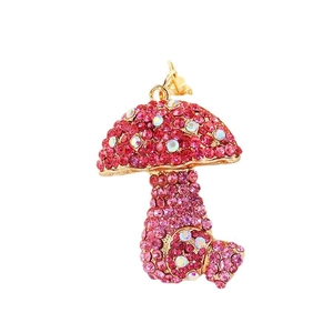Sparkling mushroom keychain with pink rhinestones and gold plating on white background