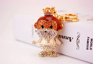 Detailed close-up of a sparkling crystal monkey keychain with golden crown on a white book