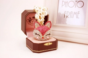 Detail of fox pendant with pink rhinestones and white pearls in a jewelry box