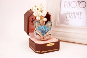 Detailed view of fox pendant with blue rhinestones and pearls in a jewelry gift box
