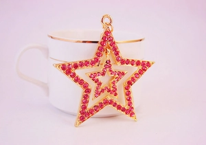 Close-up of pink rhinestone star keychain with gold plating on a decorative porcelain cup