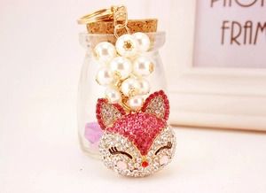 Detailed shot of golden fox keychain with white pearls and sparkling pink rhinestones
