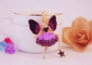 Gros plan détaillé du pendentif ange doré avec strass violets et petite breloque étoile