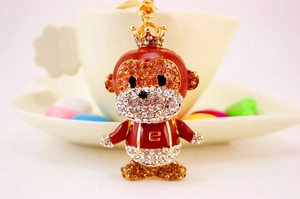Macro detail of cute crystal monkey keychain with crown and red enamel suit