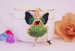 Détail des ailes d'ange en strass verts et du charme de danseuse sur bord en céramique