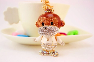 Detailed view of cartoon monkey keychain with sparkling rhinestones and white enamel outfit
