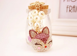 Detail of fox head keychain with rhinestones and faux pearls on a gold ring