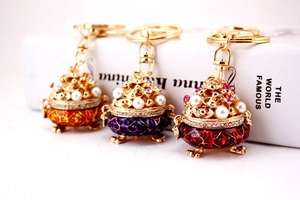Detailed close-up of colorful enamel perfume bottle keychains with pearls and crystals