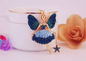 Détails du porte-clés ange aux strass bleus accroché à une tasse à café dorée
