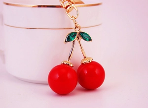 Détail du porte-clés cerises rouges avec branches dorées et feuilles en cristal vert