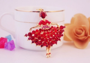 Detail of ballerina brooch with red and pink crystals on a white ceramic cup