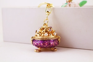 Macro detail of purple enamel censer keychain with gold metal and pearls
