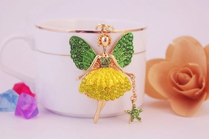Détail d'un porte-clés ange avec ailes vertes et robe en cristal jaune sur tasse blanche