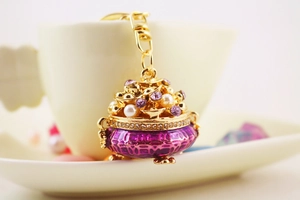 Detailed view of a golden treasure bag keychain with purple crystals and pearls