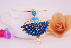 Detailed view of ballerina brooch with blue rhinestones and gold plating on coffee cup