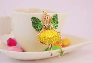 Gros plan du pendentif ange avec strass verts et jaunes et baguette en forme d'étoile