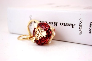 Detail of red enamel sphere keychain with gold metal accents and pearl ornaments