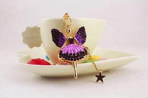 Détail du porte-clés ange fée avec strass violets et noirs sur une tasse à café