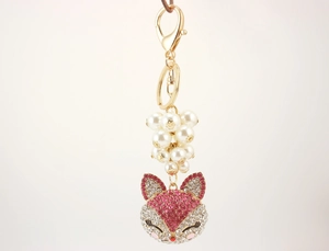 Detail of fox-shaped keychain with pink rhinestones, faux pearls and gold plating