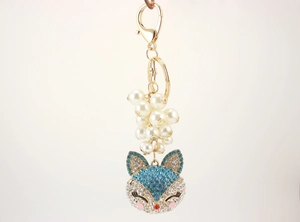 Close-up of golden fox keychain with white faux pearls and crystal encrusted fox head