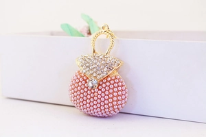 Close-up of golden purse keychain with pink pearls and sparkling rhinestones