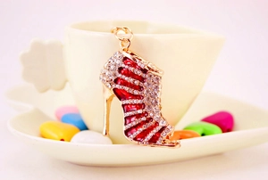 Detailed view of rhinestone high heel keychain with red enamel finish on a coffee cup