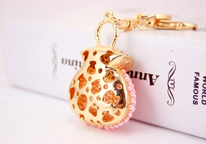 Detail of a golden handbag keychain with pink pearls and rhinestones on a white book