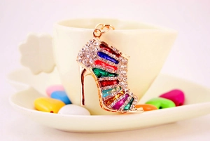 Detailed close-up of a golden high heel keychain with colorful crystals on a coffee cup