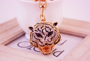 Macro detail of a golden leopard head keychain with white rhinestones and lobster clasp