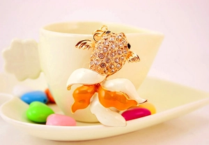 Détail d'un porte-clés poisson rouge avec émail coloré et strass brillants sur une tasse