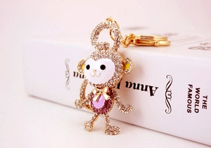Close-up of golden monkey keychain with purple crystals and white enamel finish