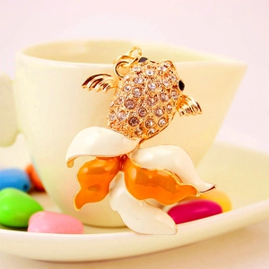 Porte-clés poisson rouge doré avec émail orange et cristaux sur une tasse blanche