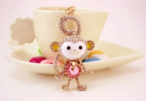 Detailed close-up of crystal monkey keychain hanging on a white ceramic coffee cup