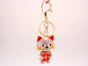 Detailed close-up of sparkling crystal-encrusted lucky cat keychain with red Zhaocai charm