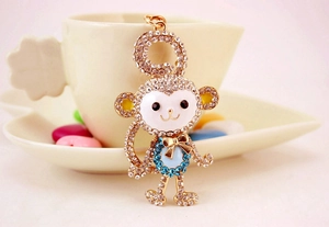 Sparkling crystal encrusted monkey keychain hanging on a white porcelain coffee cup