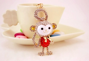 Macro detail of the crystal monkey keychain with golden bow on a white coffee cup saucer