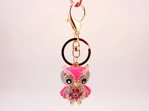 Détail d'un porte-clés hibou mignon avec finition dorée, émail rose et strass brillants