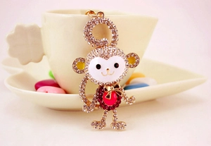 Close-up of crystal monkey keychain featuring gold frame and rose red gemstone accent