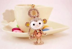 Detailed close-up of a sparkling crystal monkey keychain on a decorative heart tray