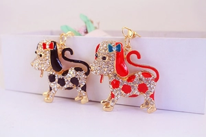 Detailed view of two rhinestone-encrusted dalmatian keychains in gold-tone alloy