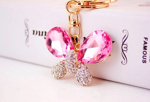 Détail d'un porte-clés papillon en cristal rose avec strass sur un livre blanc
