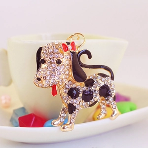 Cute spotted dog keychain with white rhinestones and black enamel in a cozy cup setting