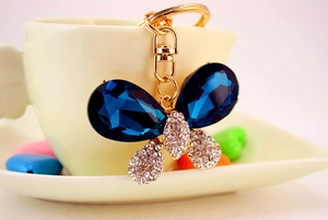 Détail du porte-clés papillon doré avec de gros strass bleus et petits cristaux