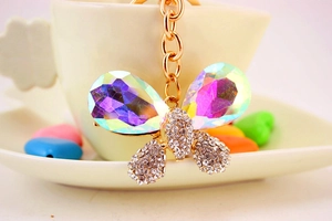 Macro d'un porte-clés papillon doré avec cristaux scintillants et gemmes sur une tasse blanche