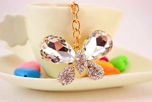 Détail d'un porte-clés papillon en cristal suspendu au bord d'une tasse blanche